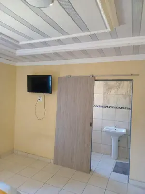 a bathroom with a toilet and a tv on the wall at Whizzy Lifestyle Lodge in Witbank