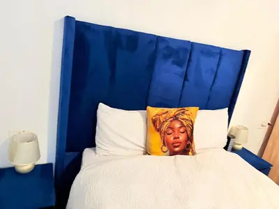 a bed with a blue headboard with a statue on it at Whizzy Lifestyle Lodge in Witbank