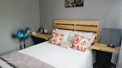 a bedroom with a bed with pillows and a fan at Matibidi Guest Lodge in Graskop