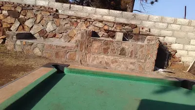 a stone wall with a pool in front of it at Matibidi Guest Lodge in Graskop