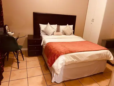 a bedroom with a large bed and a table at Eccoo OR Tambo Airport lodge in Kempton Park