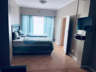 a bedroom with a bed and a large window at Eccoo OR Tambo Airport lodge in Kempton Park