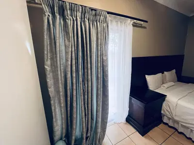 a bedroom with a bed and a window with curtains at Eccoo OR Tambo Airport lodge in Kempton Park