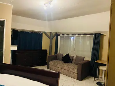 a living room with a couch and a bed at Eccoo OR Tambo Airport lodge in Kempton Park