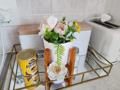a flower arrangement in a white vase on a shelf at Olympus Side in Pretoria