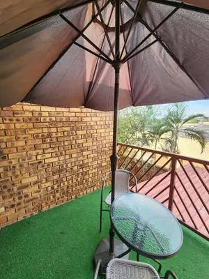 a table and a chair under an umbrella at Olympus Side in Pretoria