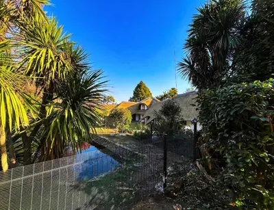 a fence in front of a house with palm trees at Wood Valley in Midrand