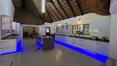 a large kitchen with white cabinets and blue lighting at Wood Valley in Midrand