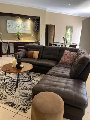 a living room with a leather couch and a table at Villa on 8 Pecanwood in Hartbeespoort