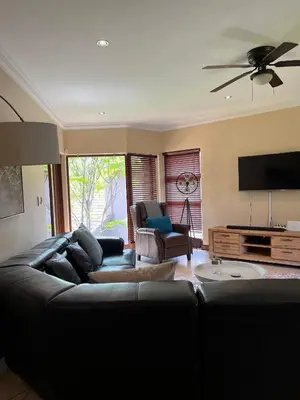a living room with a black couch and a flat screen tv at Villa on 8 Pecanwood in Hartbeespoort