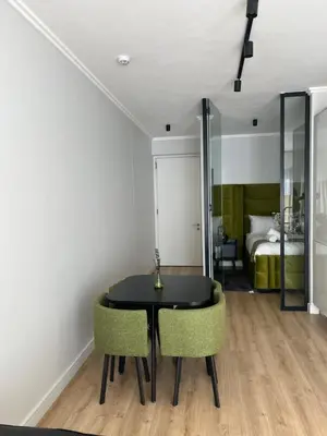 a dining room with a black table and two green chairs at Ellipse waterfall midrand in Midrand