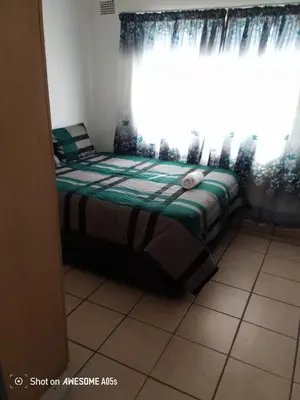 a bed sitting in a room with a window at 7 Geelhout Ave in Nelspruit