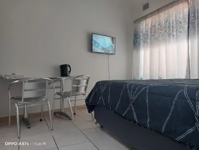 a bedroom with a bed and a table and chairs at 7 Geelhout Ave in Nelspruit
