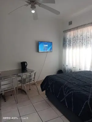 a bedroom with a bed and a desk and a ceiling fan at 7 Geelhout Ave in Nelspruit