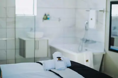 a hotel room with towels on a bed with a tub at Nyamankulu Guest Lodge in Thulamahashi