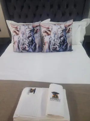 a bed with two pillows with a cow on it at Nyamankulu Guest Lodge in Thulamahashi