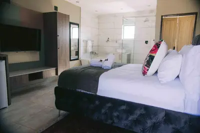 a bedroom with a large bed and a television at Nyamankulu Guest Lodge in Thulamahashi