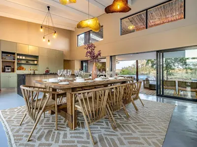 a dining room with a large wooden table and chairs at Nare Bush Lodge in Marloth Park