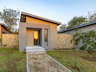 a modern house with a stone wall at Nare Bush Lodge in Marloth Park