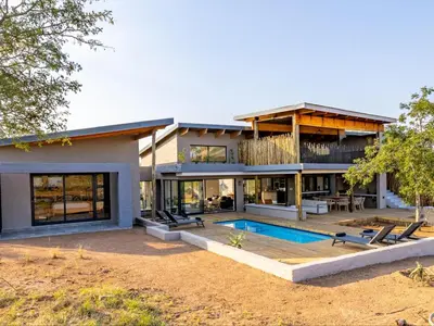 a house with a swimming pool in front of it at Nare Bush Lodge in Marloth Park
