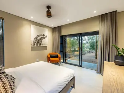 a bedroom with a bed and a chair at Nare Bush Lodge in Marloth Park