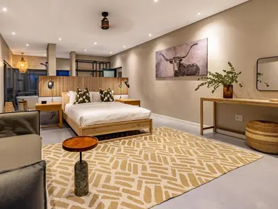 a bedroom with a bed and a living room at Nare Bush Lodge in Marloth Park
