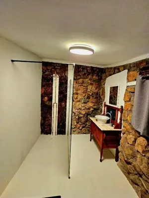 a bathroom with a stone wall and a sink at Luxury GuesthouseCo FlintstoneHouse in Marloth Park