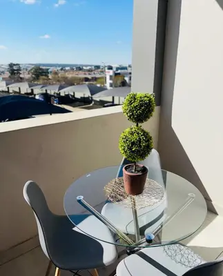 a glass table with a potted plant on a balcony at Dubai 8 in Midrand