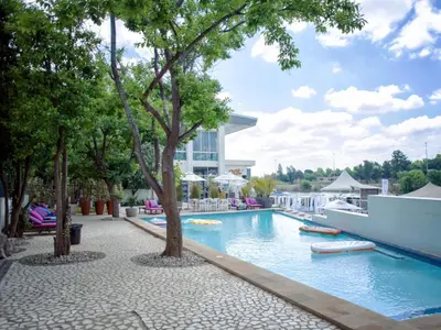 a pool at a resort with trees and a building at ANEW Hotel & Convention Centre OR Tambo Johannesburg in Benoni
