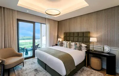 a bedroom with a bed and a chair and a window at Steyn City Hotel by Saxon in Midrand