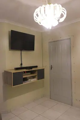 a living room with a flat screen tv and a chandelier at Zone 4 Motel in Polokwane
