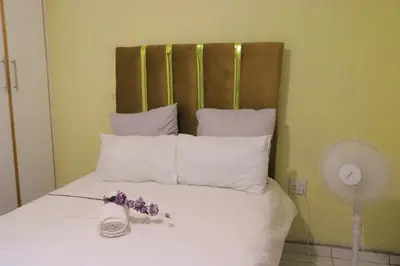 a bed with white pillows and purple flowers on it at Zone 4 Motel in Polokwane