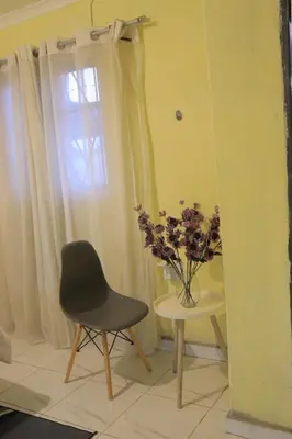 a chair and a table with a vase of flowers at Zone 4 Motel in Polokwane