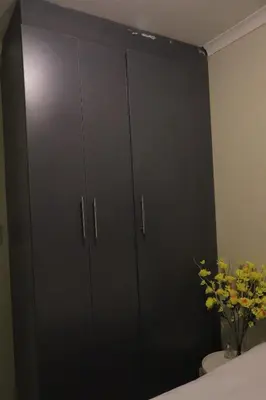 a large black cabinet in a bedroom with flowers at Zone 4 Motel in Polokwane