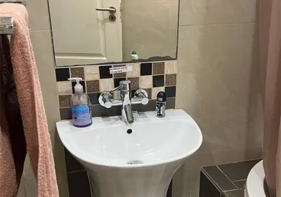a bathroom with a white sink and a mirror at The Rhino Room at Frederick's Place in Pretoria