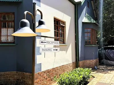 a street light with directional signs in front of a building at Kniff un Gaffel Guest House in Pretoria