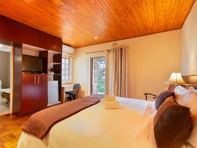 a bedroom with a large bed with a wooden ceiling at Kniff un Gaffel Guest House in Pretoria