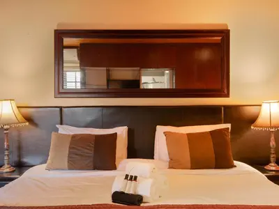 a bedroom with a bed with a mirror above it at Kniff un Gaffel Guest House in Pretoria