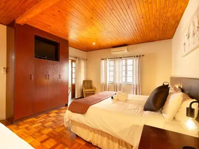 a bedroom with a large bed with a wooden ceiling at Kniff un Gaffel Guest House in Pretoria