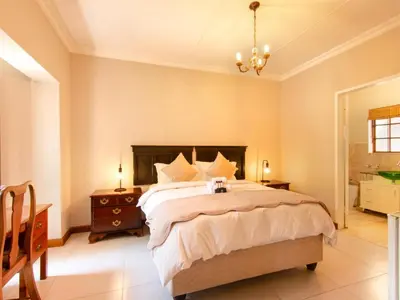 a bedroom with a large bed and a chandelier at Kniff un Gaffel Guest House in Pretoria