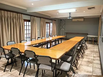 a row of tables and chairs in a room at Kniff un Gaffel Guest House in Pretoria