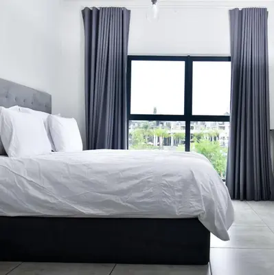 a bedroom with a bed with white sheets and a window at Feelathome in Midrand