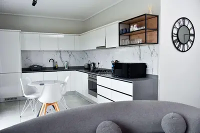 a kitchen with white cabinets and a table and a clock at Feelathome in Midrand
