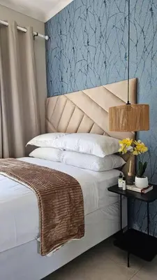 a bedroom with a bed with a blue wall at Lizzy's Residence in Midrand