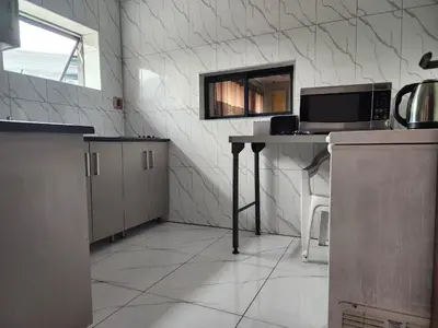 a kitchen with a counter and a table with a microwave at Duplessis Lodge in Kempton Park