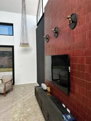a living room with a red brick wall with a tv at Rattlesnake Weir in Dullstroom