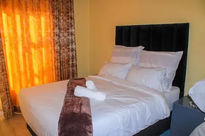 a bed with white pillows and a tie on it at Vuyani Guest Lodge in Malamulele