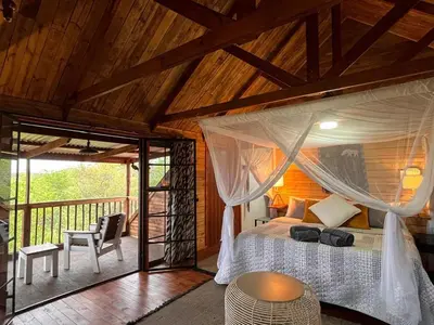 a bedroom with a canopy bed and a balcony at Croc's Nest Bush Lodge in Marloth Park