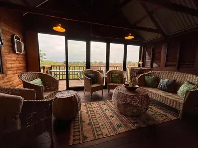 a living room with a couch and chairs and windows at Croc's Nest Bush Lodge in Marloth Park