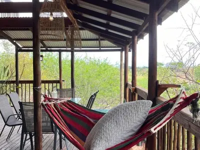 a hammock on a deck with a table and chairs at Croc's Nest Bush Lodge in Marloth Park